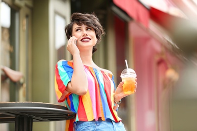 Young woman with cup of tasty lemonade outdoors