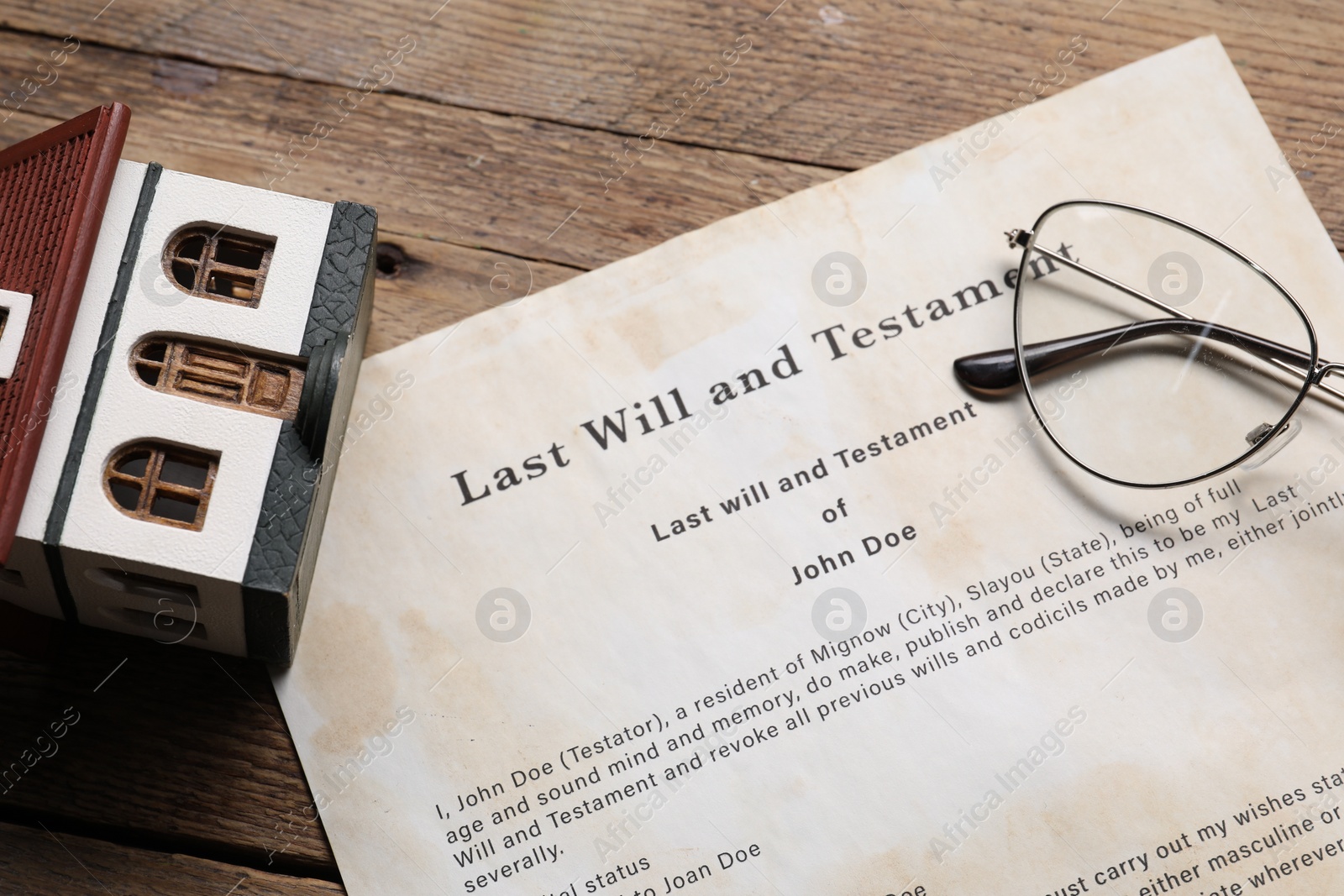 Photo of Last Will and Testament, house model and glasses on wooden table, closeup