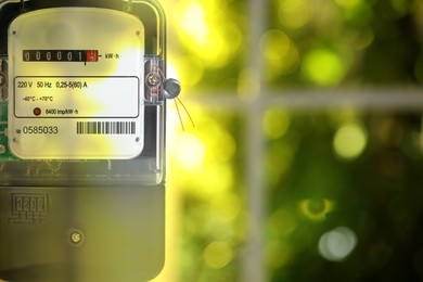 Electricity meter against blurred green background, space for text