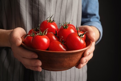 Woman holding wooden bowl with ripe cherry tomatoes, closeup