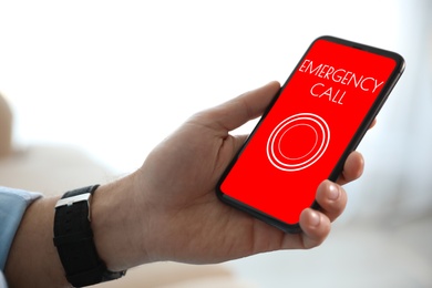 Hotline service. Man making emergency call via smartphone indoors, closeup