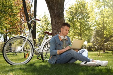 Man with cup of coffee working on laptop in park