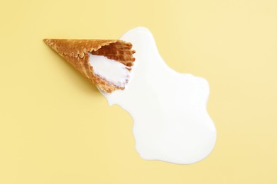 Photo of Melted ice cream and wafer cone on beige background, top view