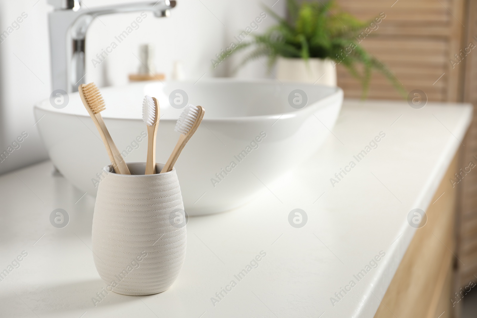 Photo of Bamboo toothbrushes on white countertop in bathroom, space for text