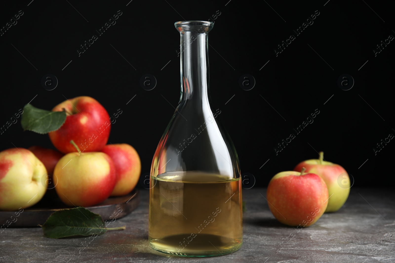 Photo of Natural apple vinegar and fresh fruits on grey table