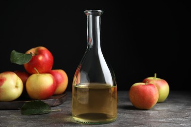 Natural apple vinegar and fresh fruits on grey table