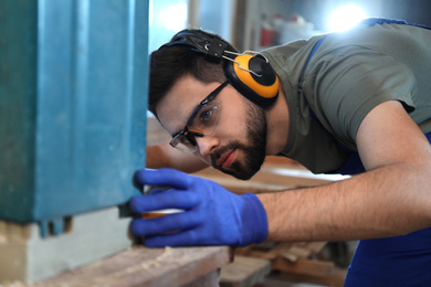 Photo of Professional carpenter working with grinding machine in shop