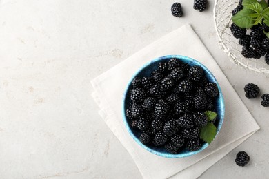 Photo of Tasty ripe blackberries and leaves on light table, flat lay. Space for text