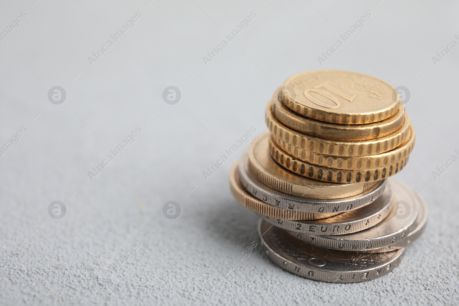 Photo of Many Euro coins stacked on white table, space for text
