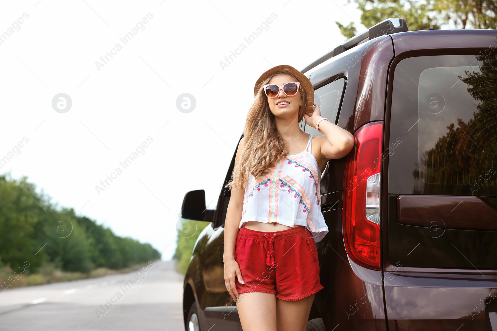 Photo of Beautiful young woman standing near car on road. Joy in moment