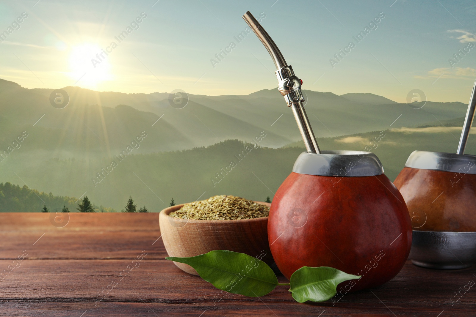 Image of Calabash with mate tea and bombilla on wooden table and beautiful view of mountain landscape, space for text