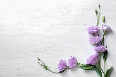 Flat lay composition with beautiful Eustoma flowers on light wooden background