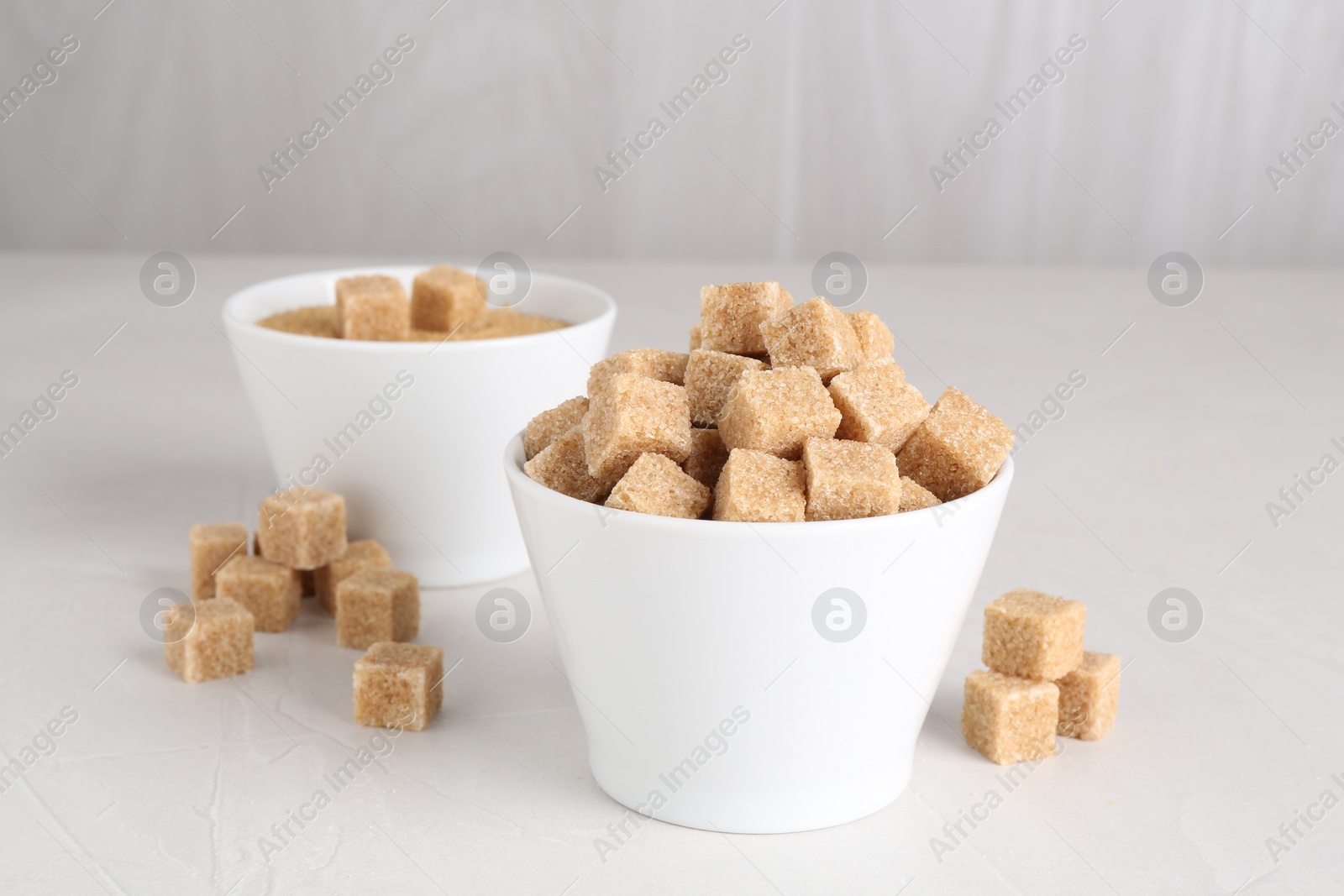 Photo of Brown sugar cubes on light textured table, closeup