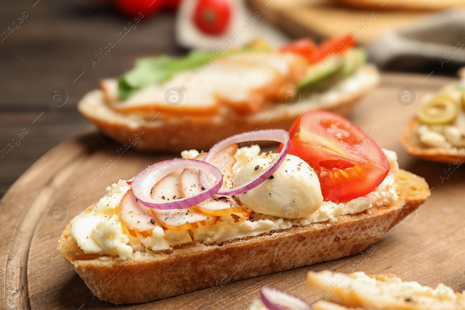 Photo of Delicious chicken bruschettas on wooden board, closeup