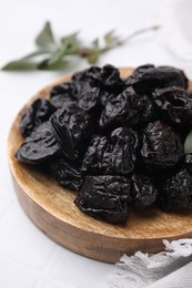 Photo of Sweet dried prunes on white table, closeup