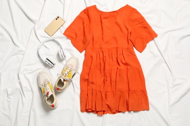 Flat lay composition with stylish orange dress on white fabric