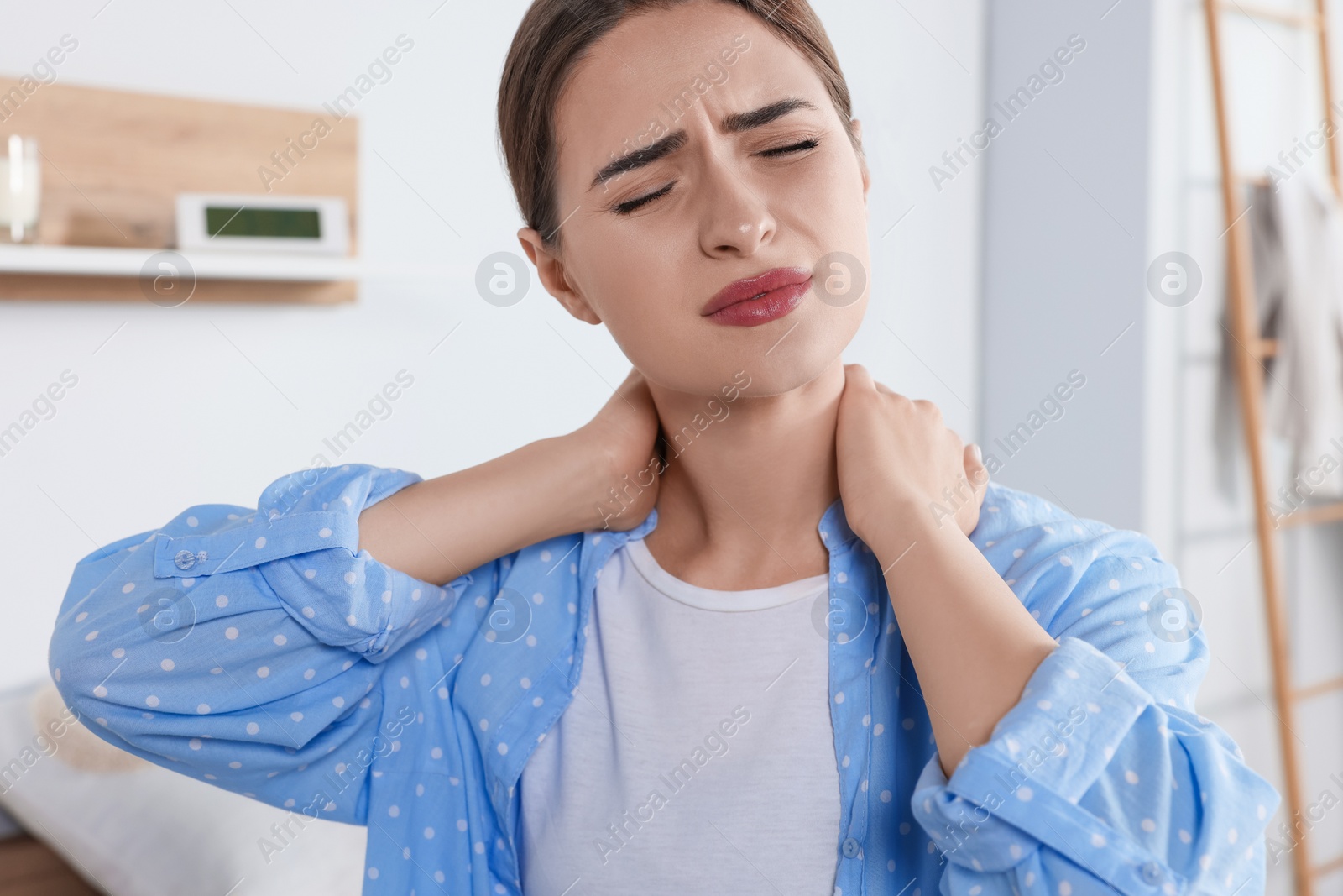 Photo of Woman suffering from neck pain in room