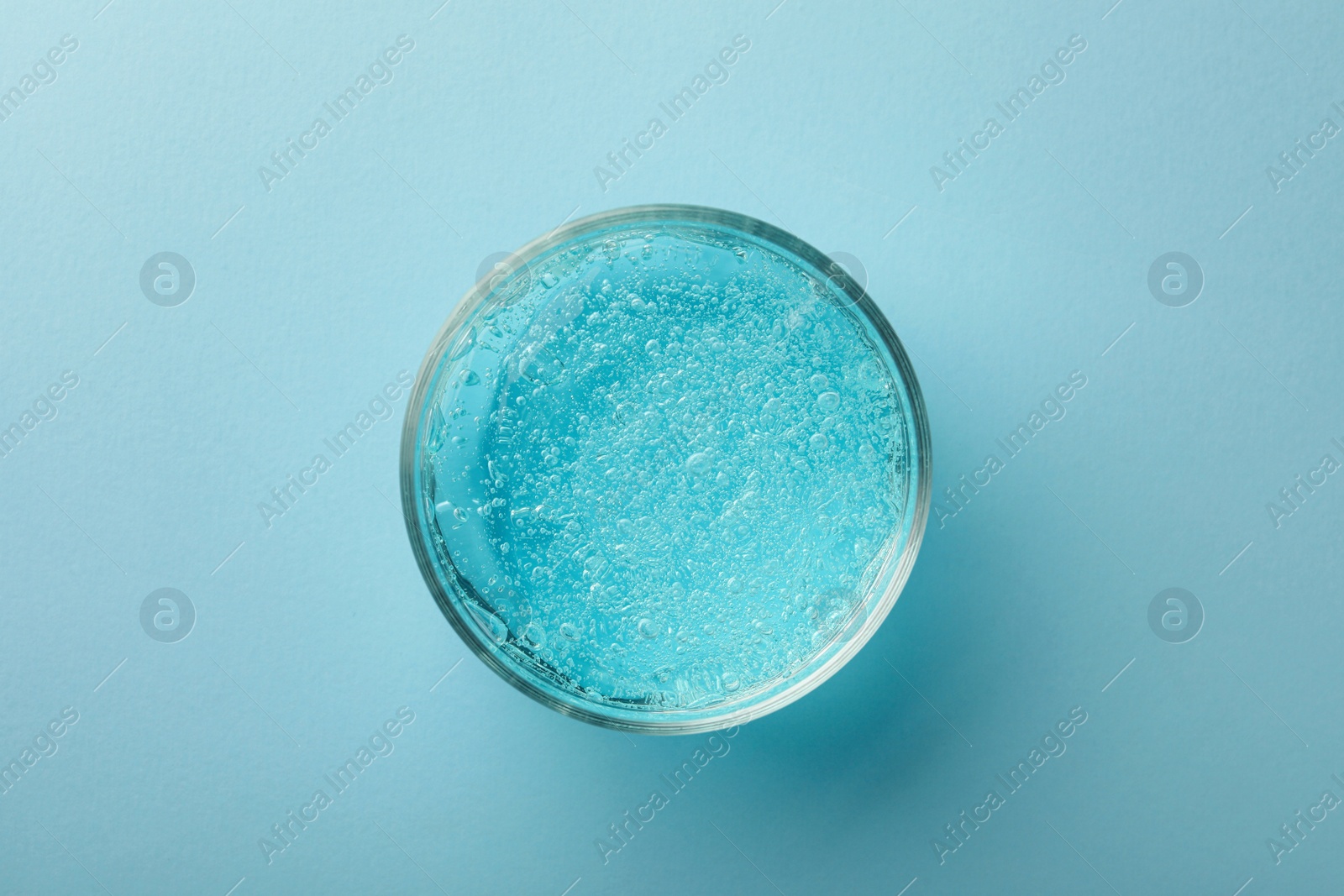 Photo of Jar of cosmetic gel on light blue background, top view