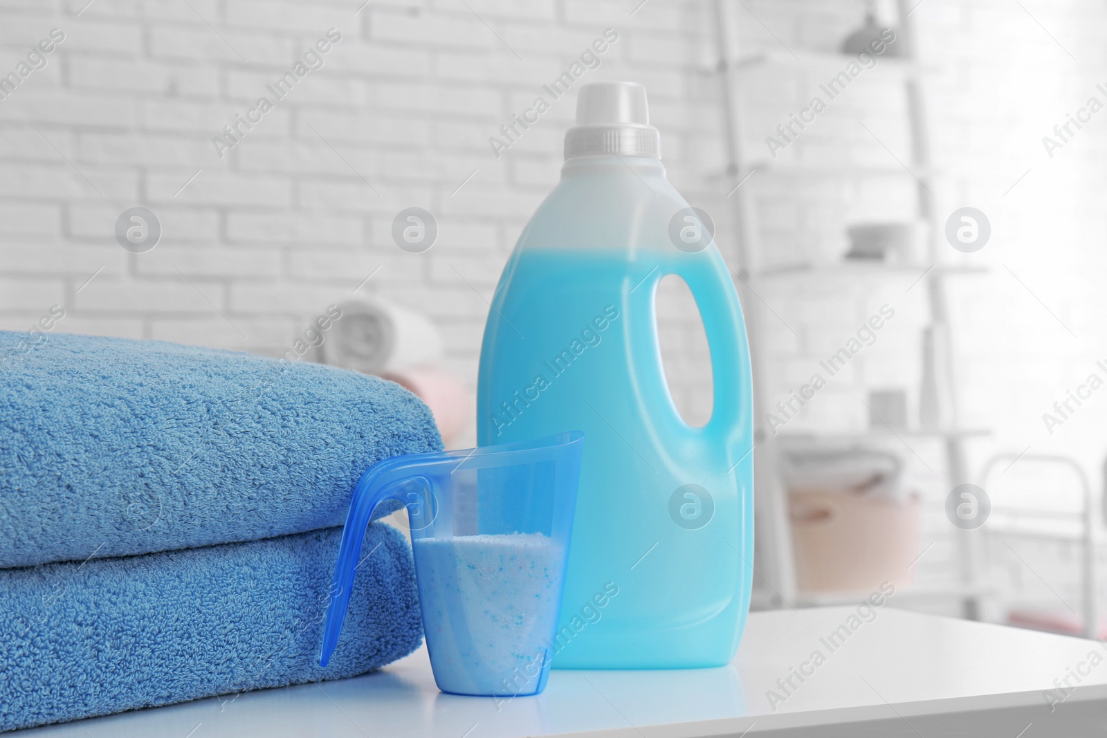 Photo of Detergents and clean towels on table indoors, space for text. Laundry day