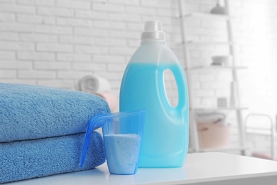 Detergents and clean towels on table indoors, space for text. Laundry day