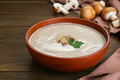Photo of Delicious mushroom cream soup with parsley on wooden table