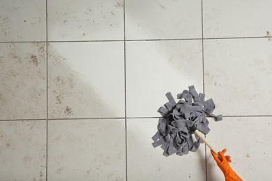 Professional cleaner washing dirty floor with mop, top view. Space for text