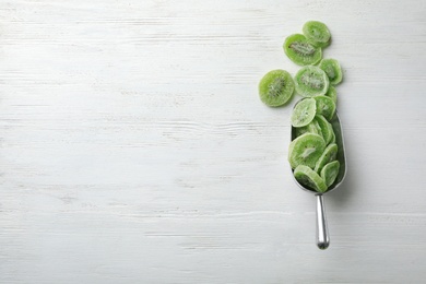 Photo of Scoop of dried kiwi on wooden background, top view with space for text. Tasty and healthy fruit
