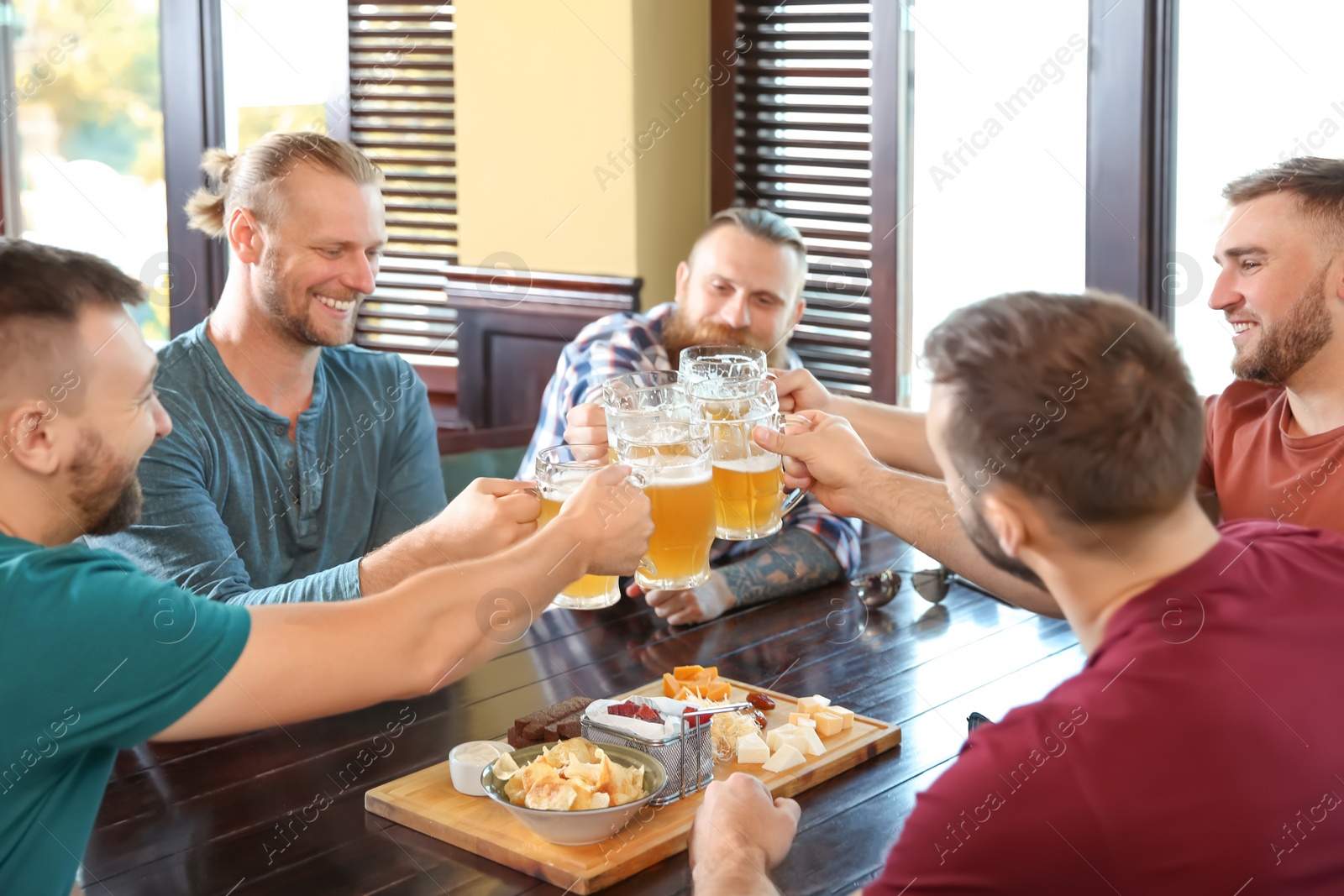 Photo of Friends clinking glasses with beer in pub