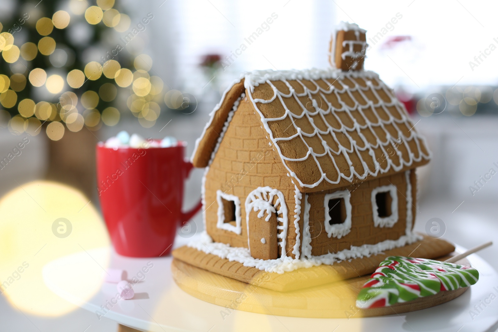 Photo of Beautiful gingerbread house decorated with icing on white table indoors