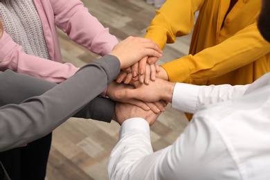 Photo of Young people putting their hands together indoors, closeup