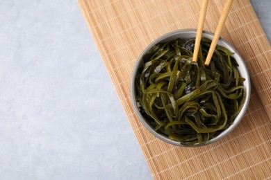 Tasty seaweed salad in bowl served on gray table, top view. Space for text