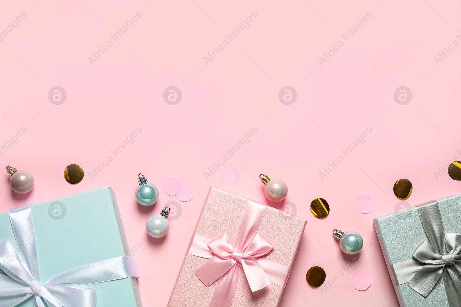 Photo of Beautiful gift boxes, Christmas balls and confetti on pink background, flat lay. Space for text