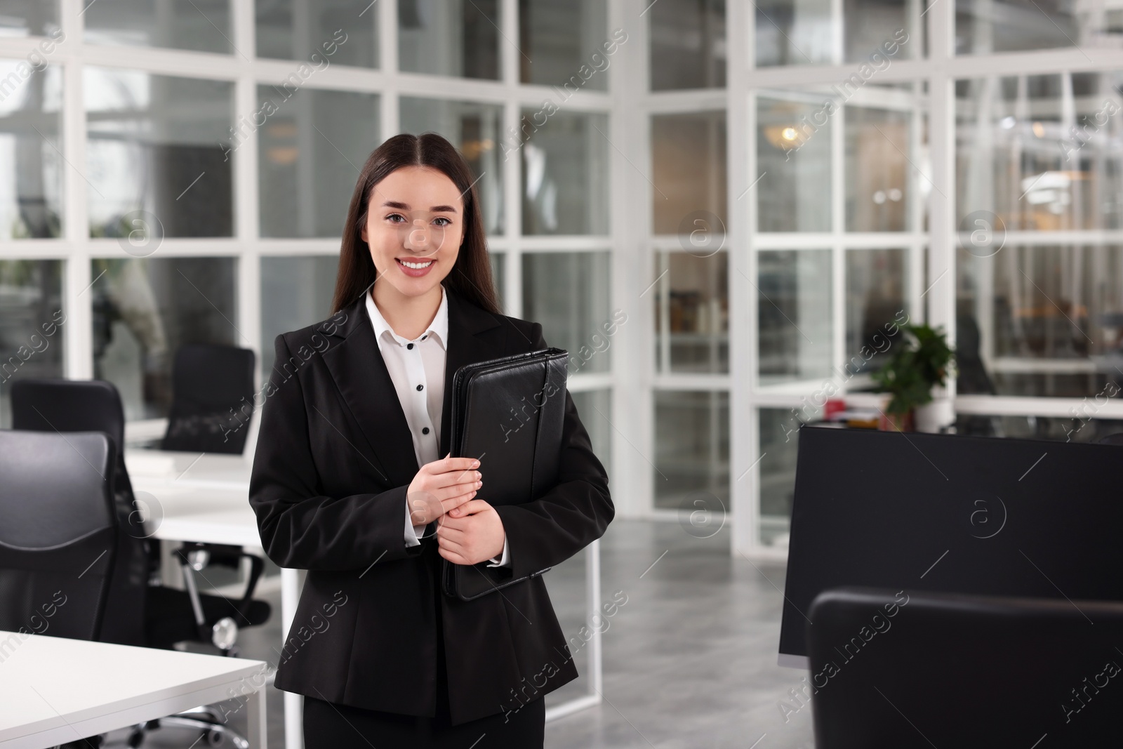 Photo of Happy real estate agent with leather portfolio in office