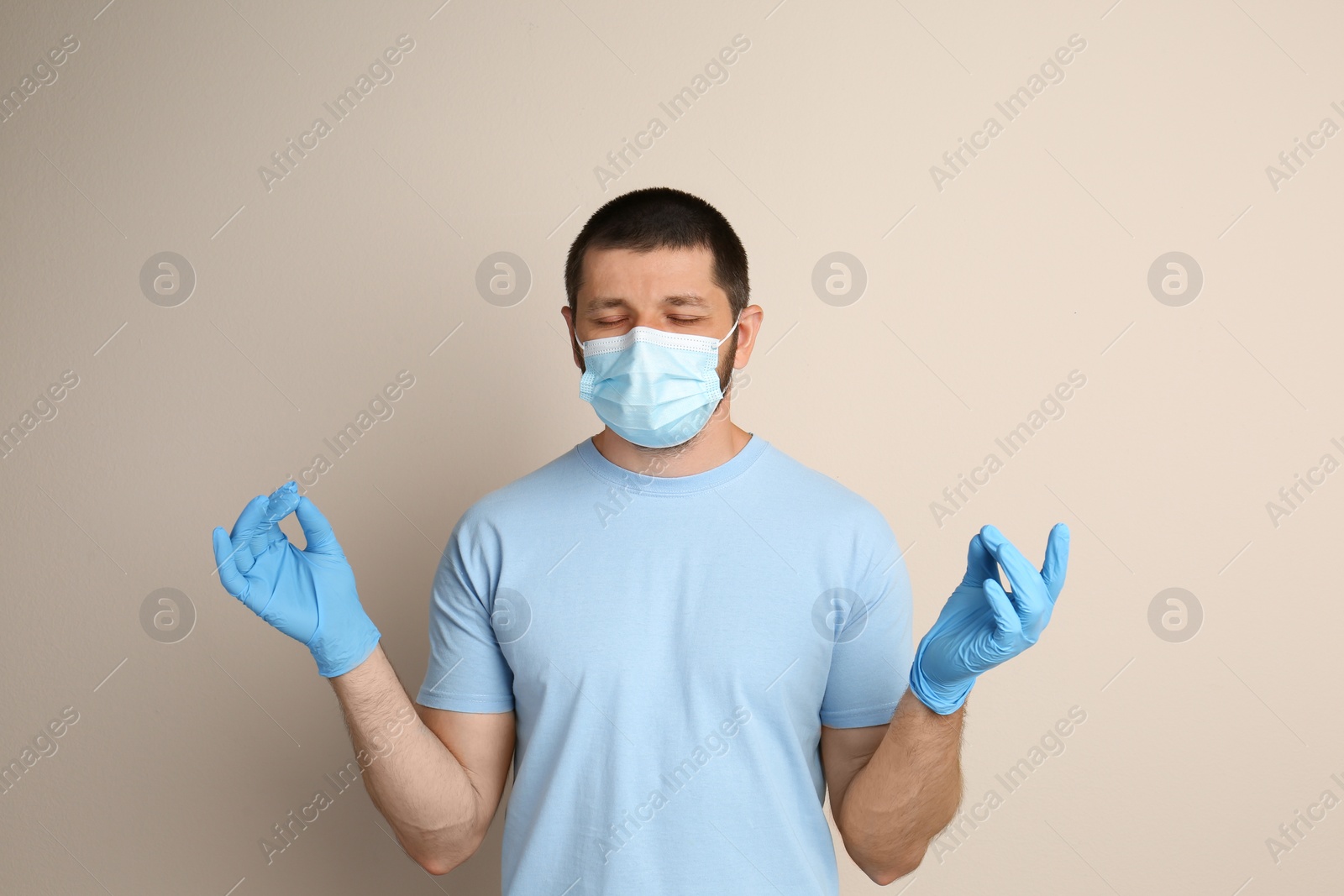 Photo of Man in protective mask meditating on beige background. Dealing with stress caused by COVID‑19 pandemic