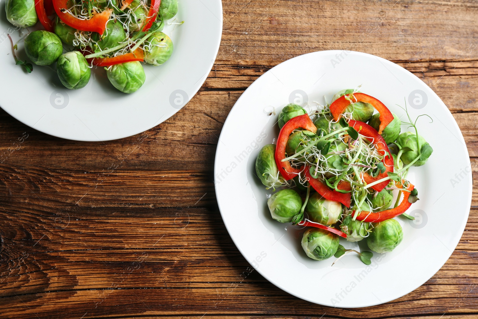 Photo of Tasty salad with Brussels sprouts on wooden table, flat lay