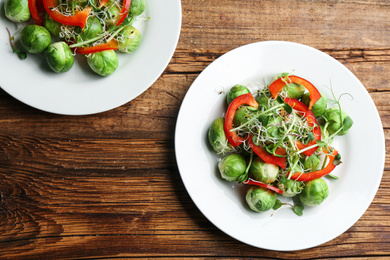 Photo of Tasty salad with Brussels sprouts on wooden table, flat lay