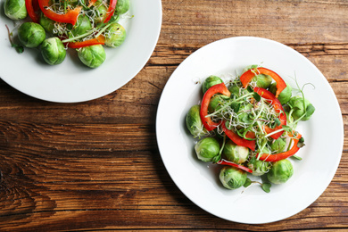 Tasty salad with Brussels sprouts on wooden table, flat lay