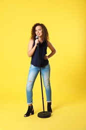 Photo of Curly African-American woman posing with microphone on color background