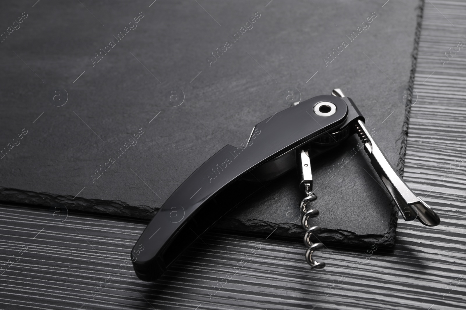 Photo of One corkscrew (sommelier knife) on black wooden table