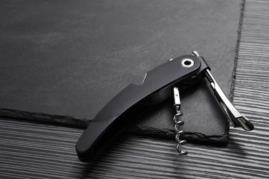 Photo of One corkscrew (sommelier knife) on black wooden table