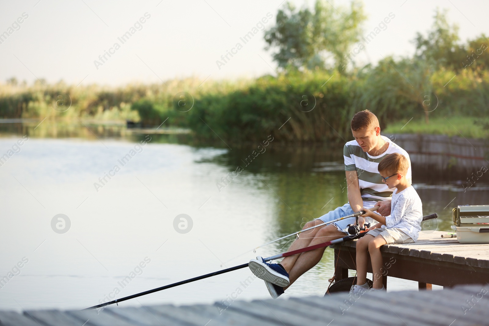 Photo of Dad and son fishing together on sunny day