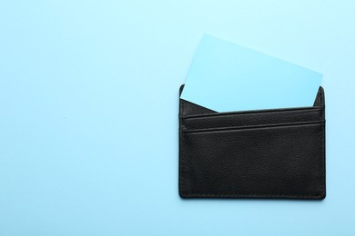 Photo of Leather business card holder with blank cards on light blue background, top view. Space for text