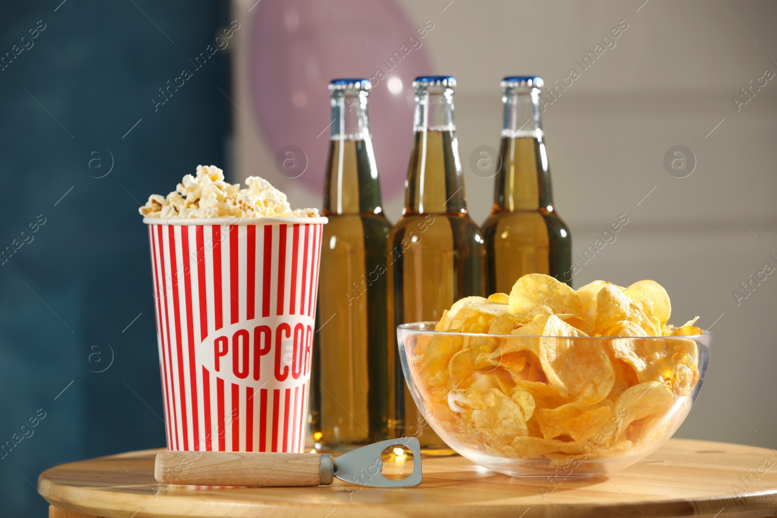 Photo of Beer, snacks and bottle opener on wooden table indoors. Party time