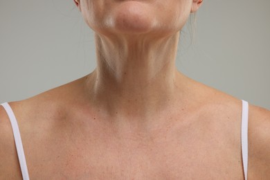 Mature woman with healthy skin on grey background, closeup