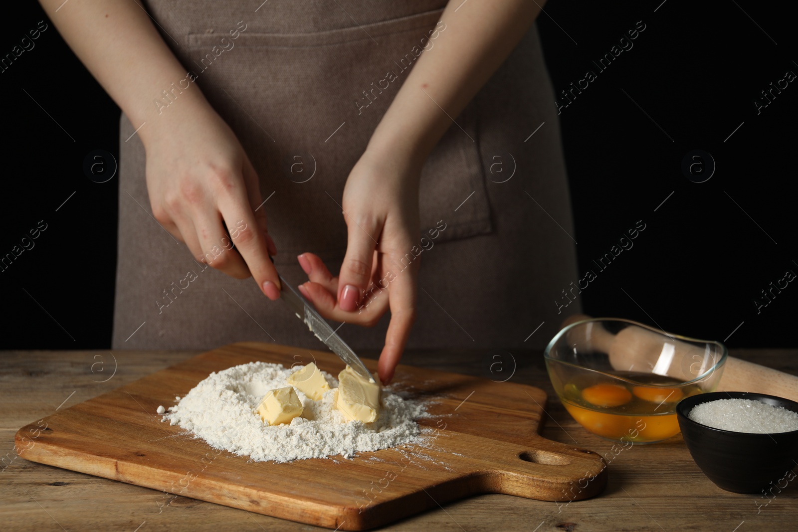 Photo of Woman cutting fresh butter at wooden table, closeup