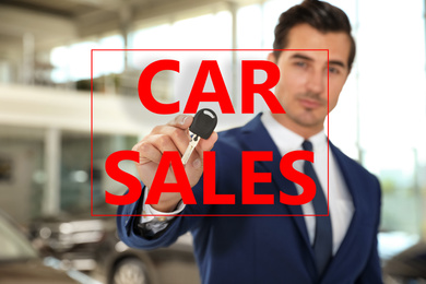 Salesman with key in car dealership, focus on hand