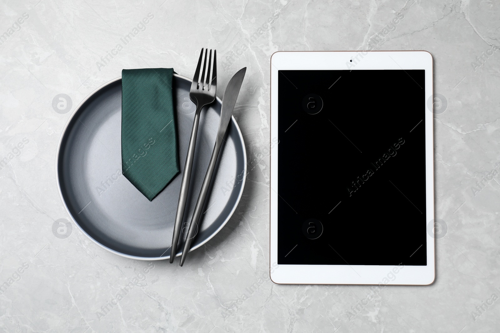 Photo of Business lunch concept. Plate, cutlery, tie and tablet with space for text on light gray marble table, flat lay