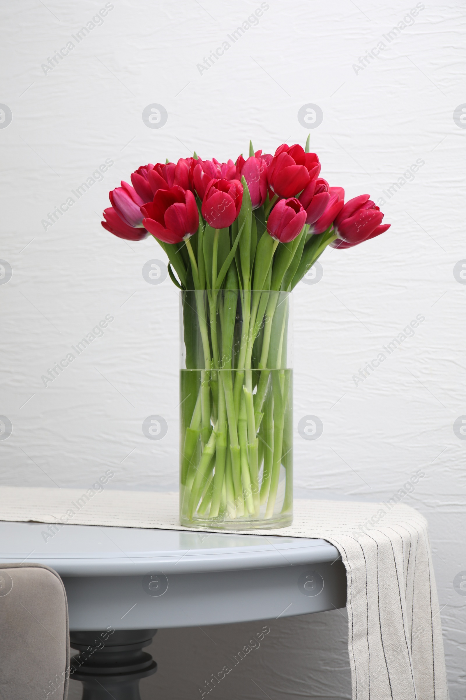 Photo of Bouquet of beautiful tulips in glass vase on table indoors