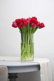 Bouquet of beautiful tulips in glass vase on table indoors