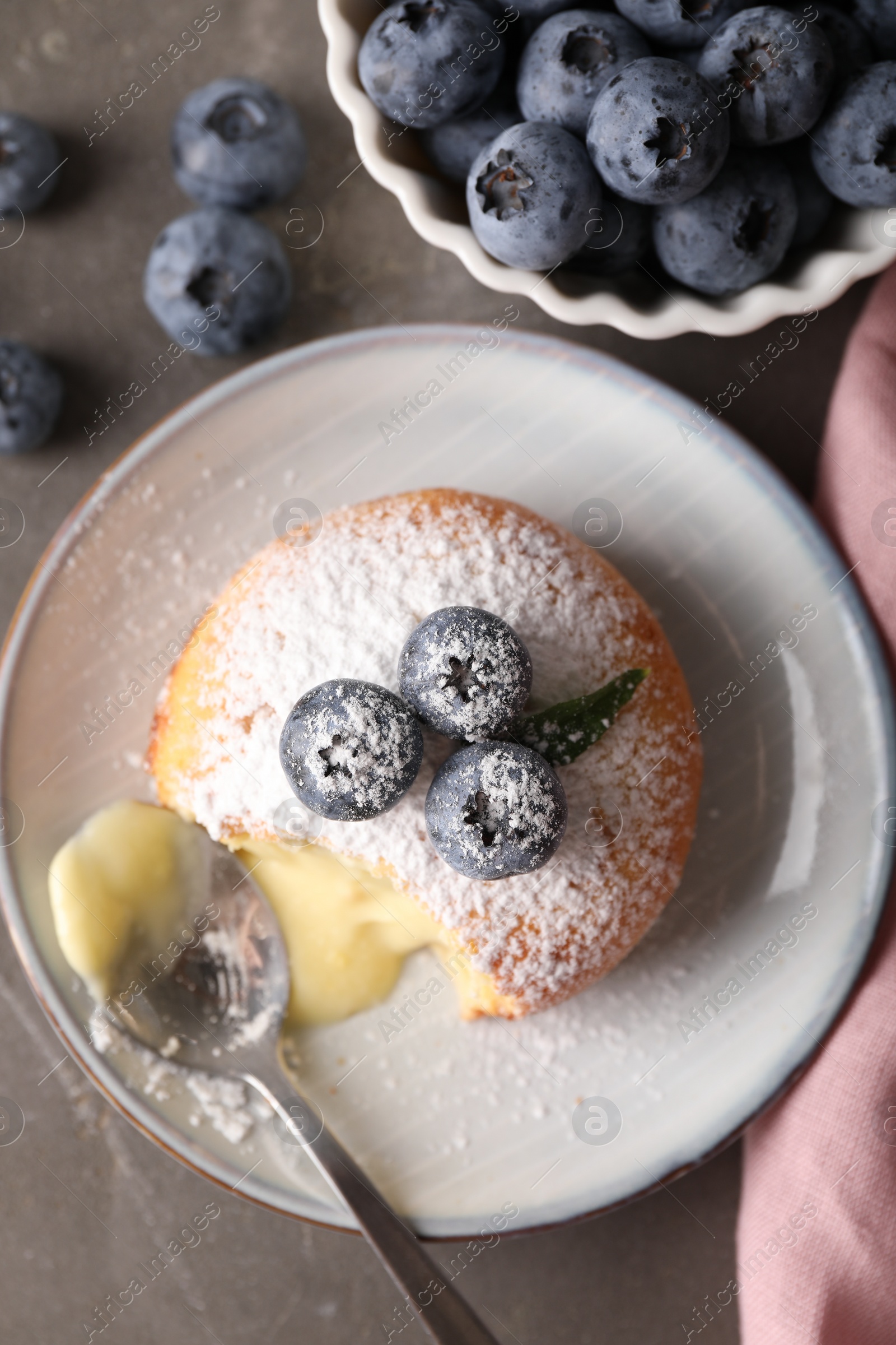 Photo of Tasty vanilla fondant with white chocolate and blueberries on grey table, flat lay